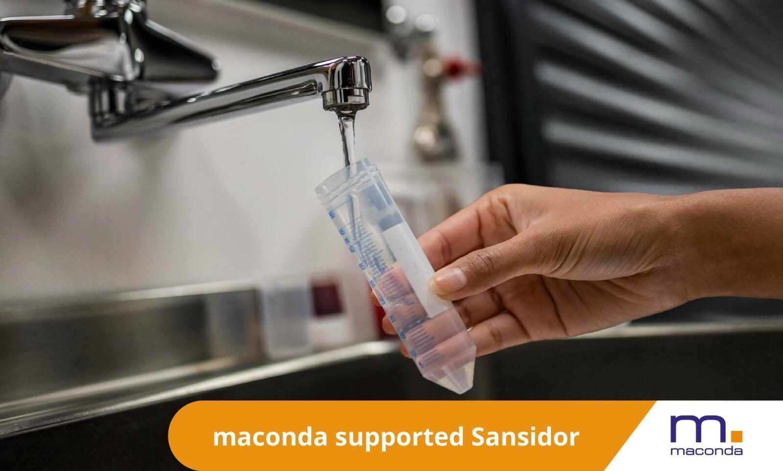 maconda News Deal Banner Sansidor x LGBA 250519 - maconda A hand holds a transparent syringe under a running faucet over a stainless steel sink
