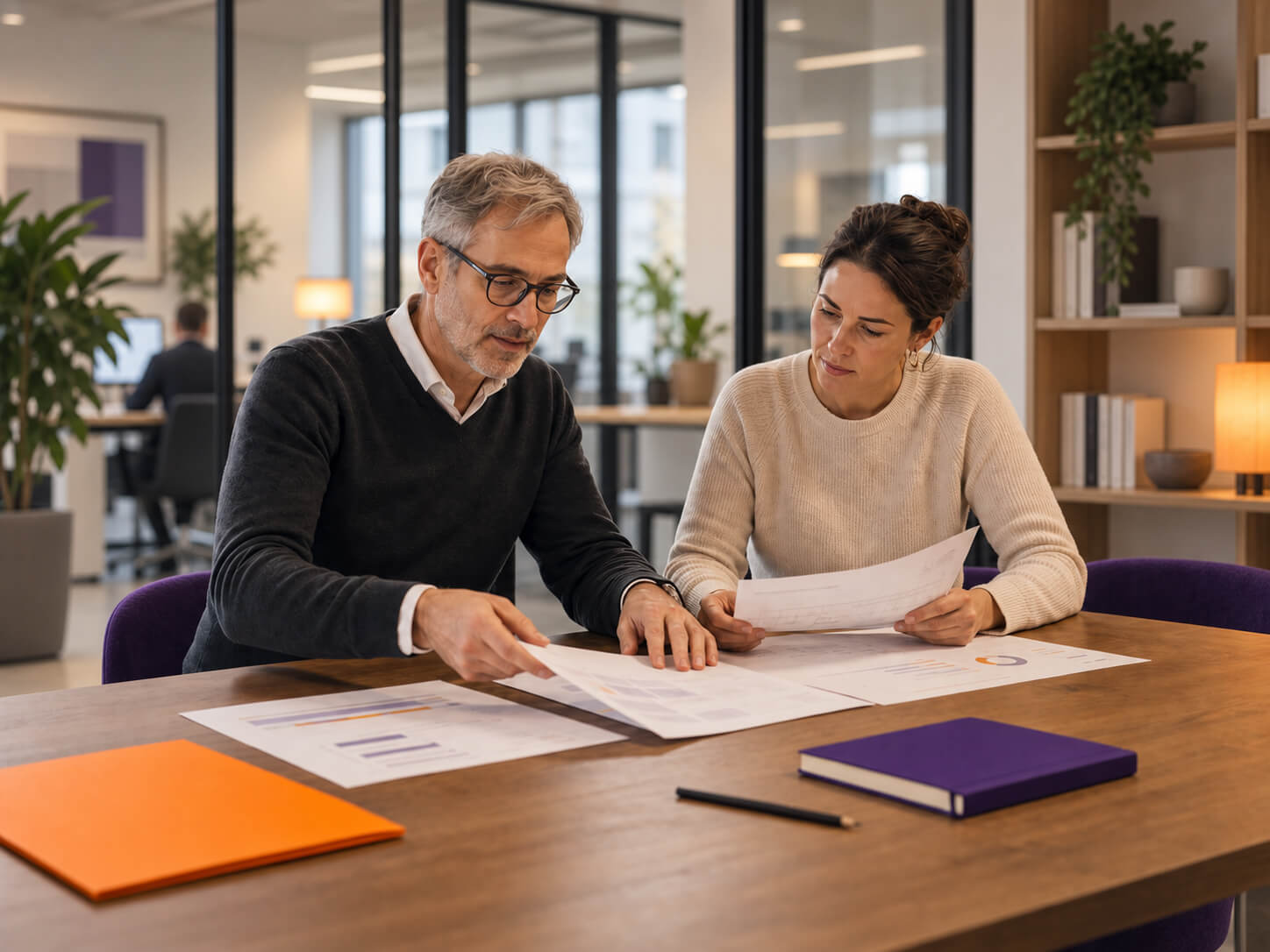 maconda-restrukturierung - maconda Zwei Kollegen besprechen Unterlagen an einem großen Holztisch in einem modernen Büro