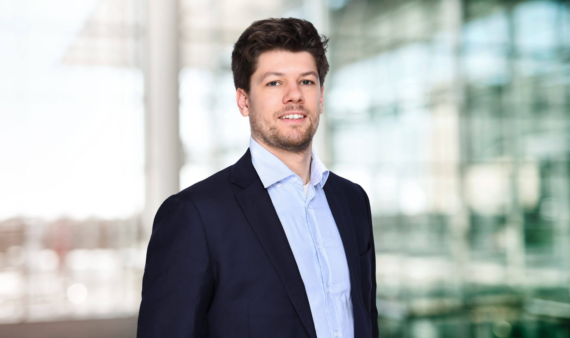 Porträt von Max Kirschbauer maconda in dunklem Blazer und hellblauem Hemd in einem modernen Büro